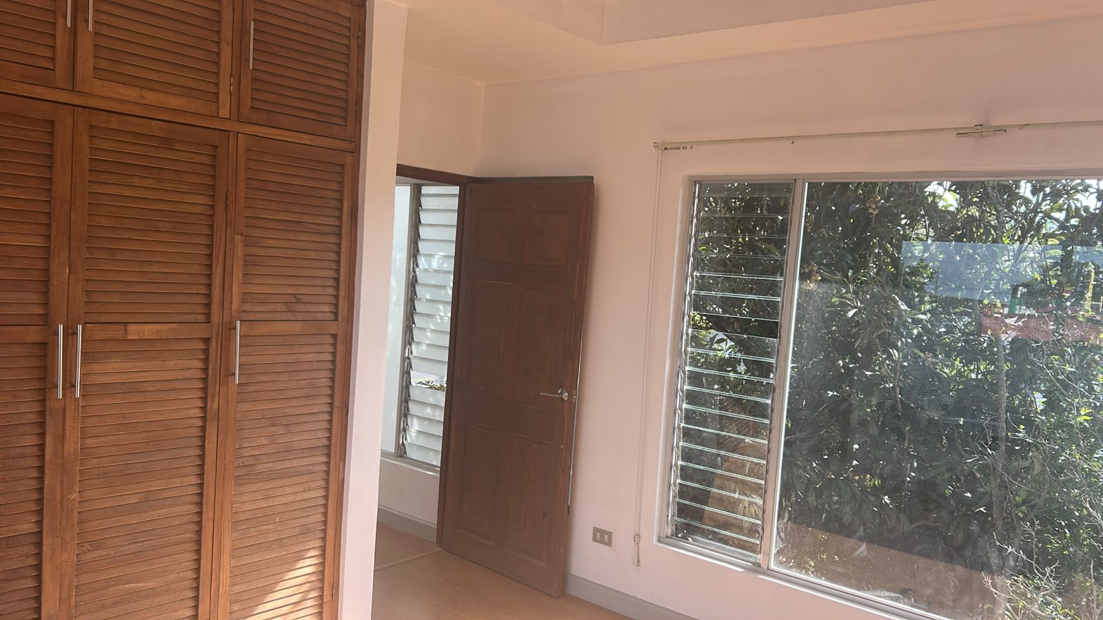 Habitación con closet de madera y ventana hacia el verde