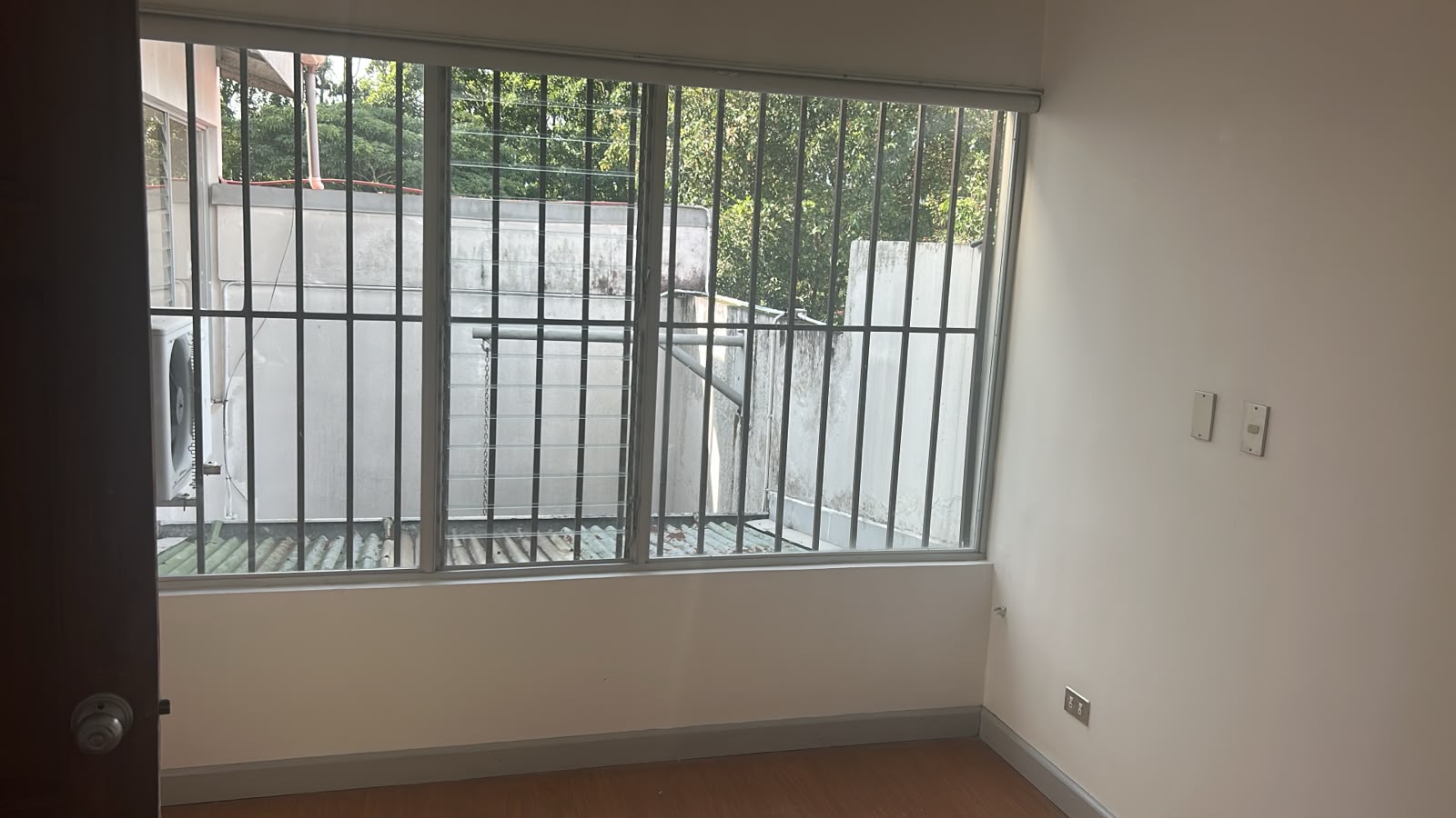 Habitación con ventana grande y vegetación al fondo